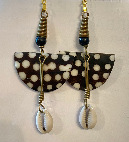 Pair of earrings with polka dot design and cowrie shell elements on a white background