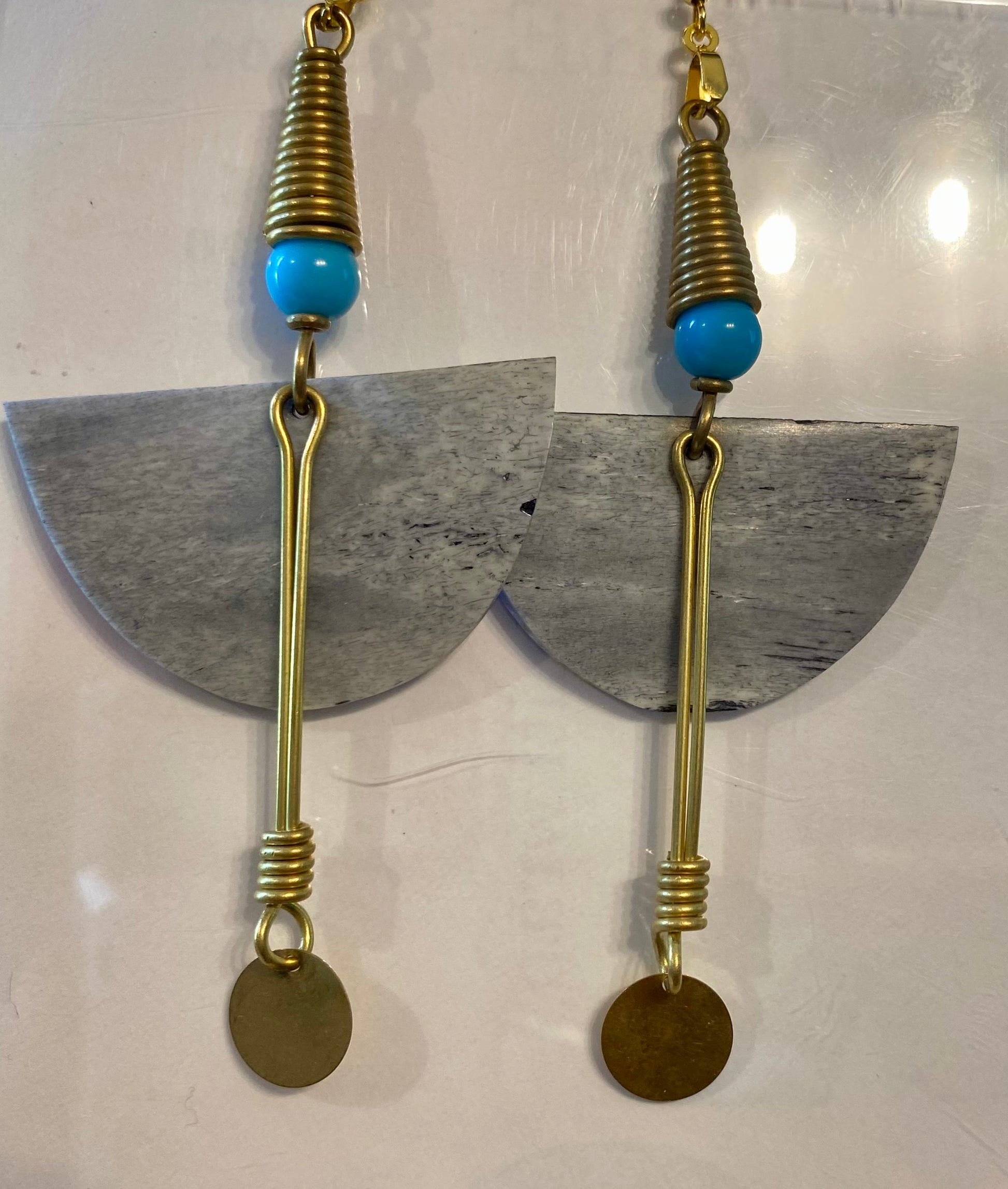 Earrings with gold elements, turquoise beads, and half-circle shapes on a white background