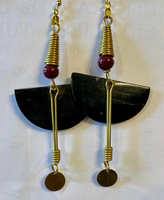 Pair of earrings with black semi-circular stones, gold loops, and red beads on a white background.