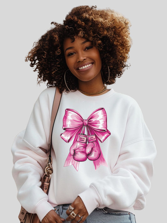 Woman wearing a white sweatshirt with a pink bow design on a plain background