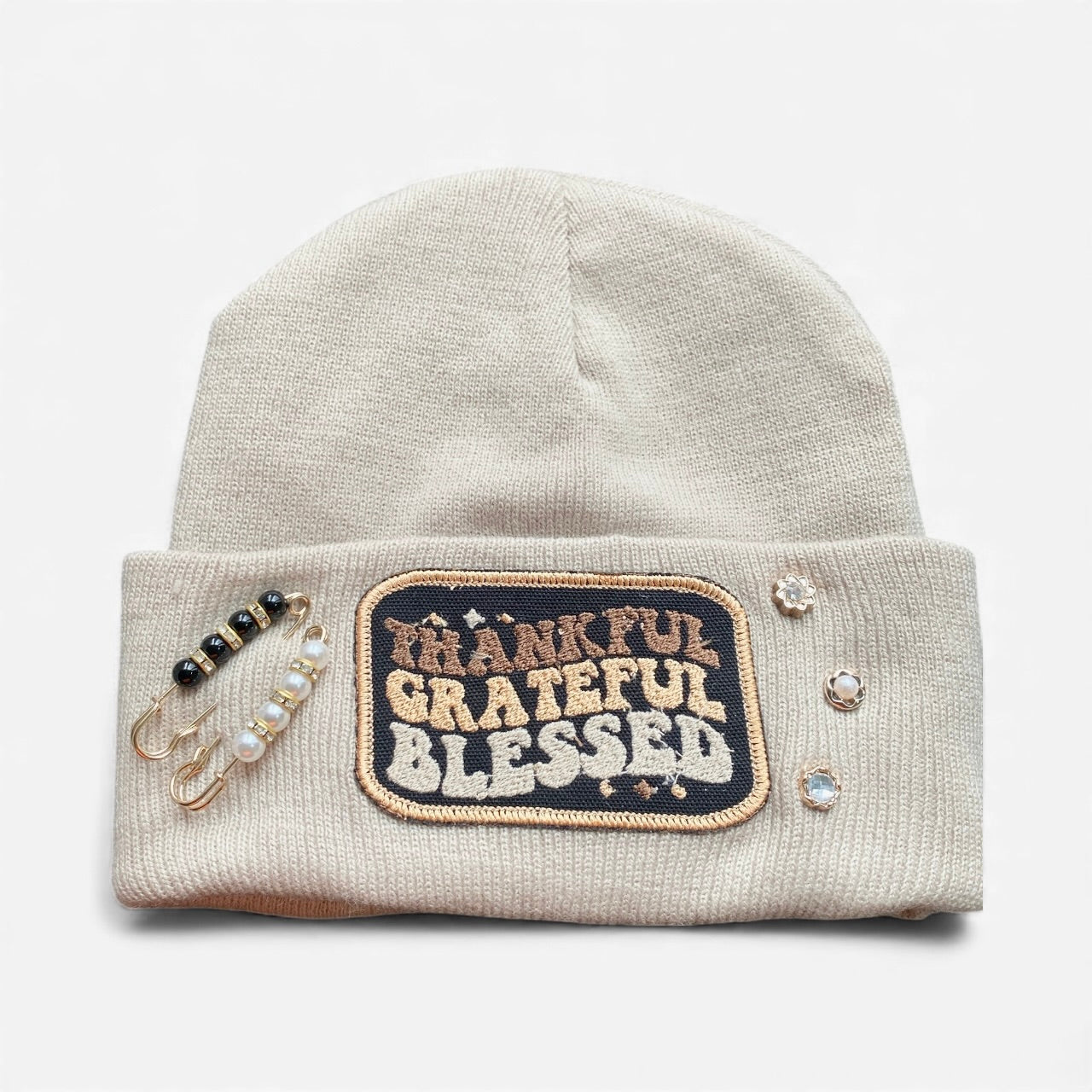 Beige beanie with 'Thankful Grateful Blessed' patch and decorative elements on a white background