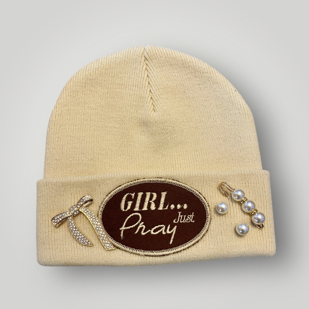 Beige beanie with decorative patch and brooches on a gray background